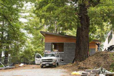 construction truck in front of a new buidling near redwood trees 