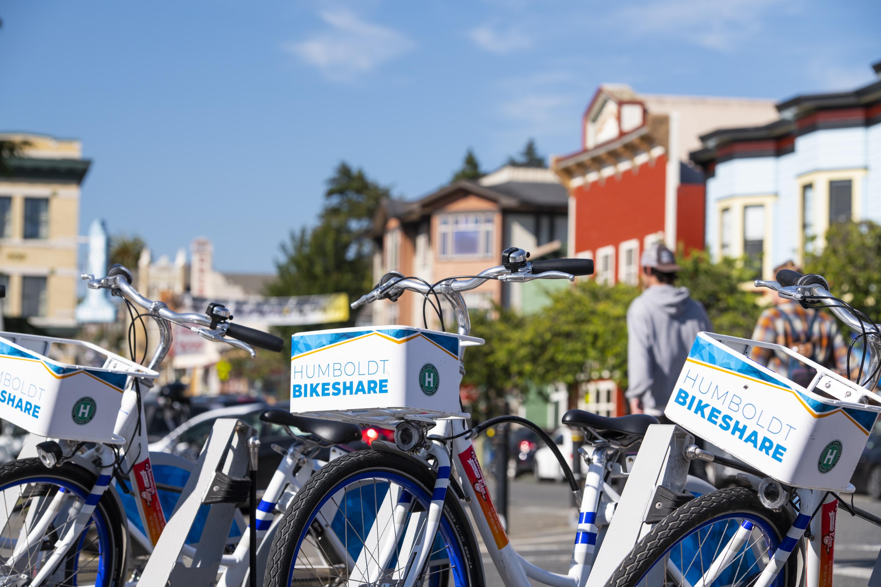 Image shows bikes from the Humboldt Bikeshare all locked up in a line at their station on the Arcata Plaza. 