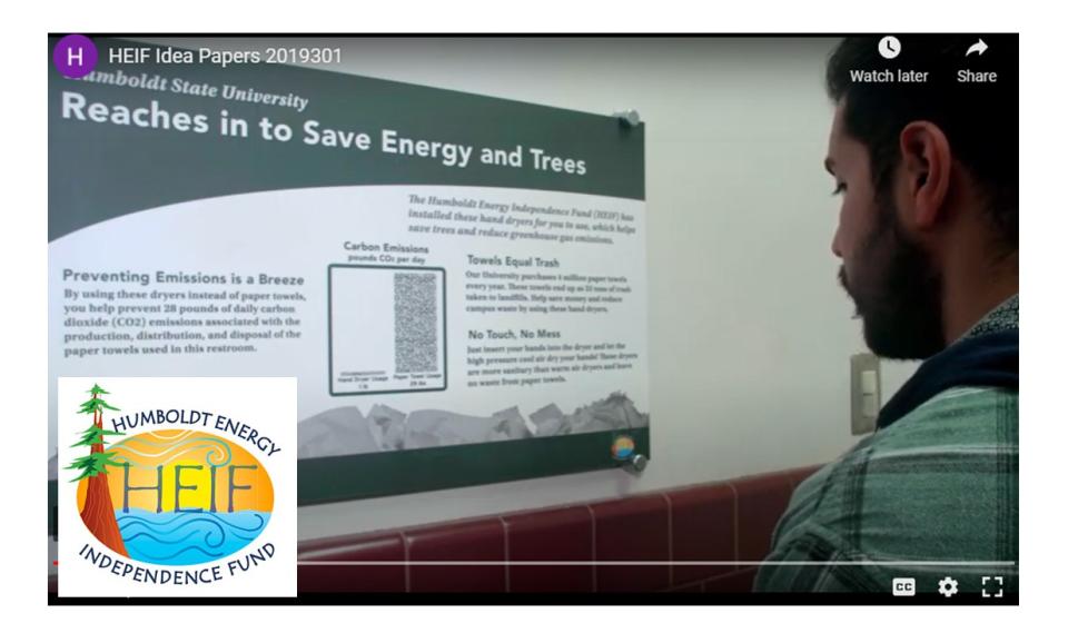Image shows a student reading a sign about a HEIF funded project installed in the Library: hand dryers which save energy and min