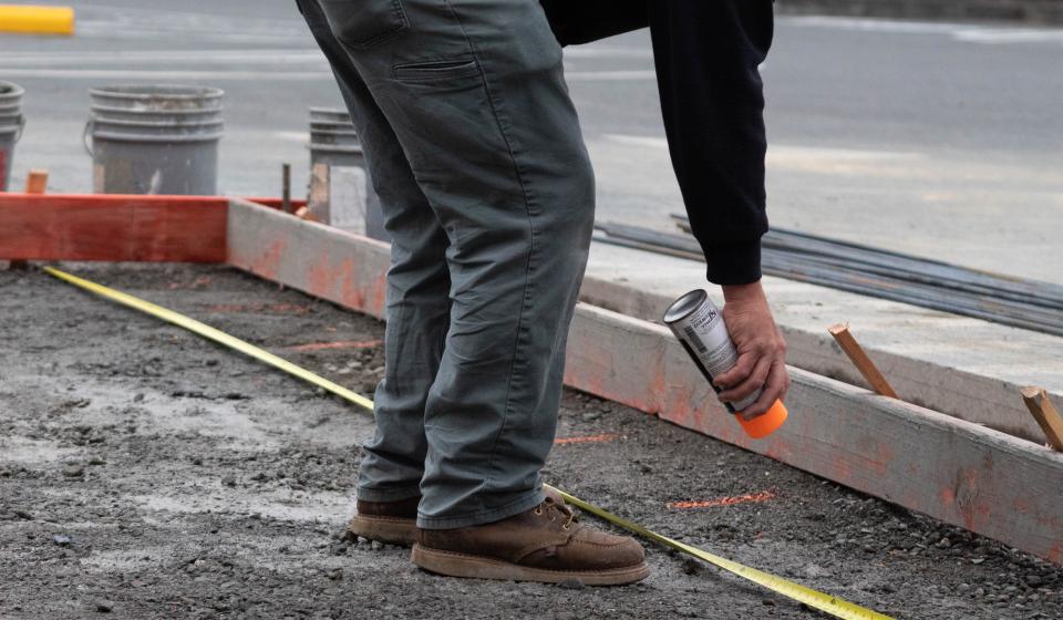 person using spray can to mark on ground for concrete pour